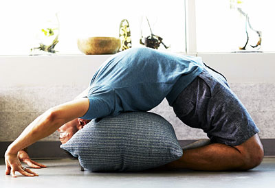 Mann übt Yoga auf einem Bolster-Kissen