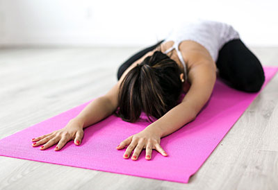 Frau macht Yoga Übungen auf einer Yogamatte